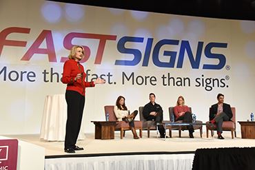 Catherine on stage at the 2015 FASTSIGNS International Convention, hosting an advocacy panel with FASTSIGNS franchisees.	